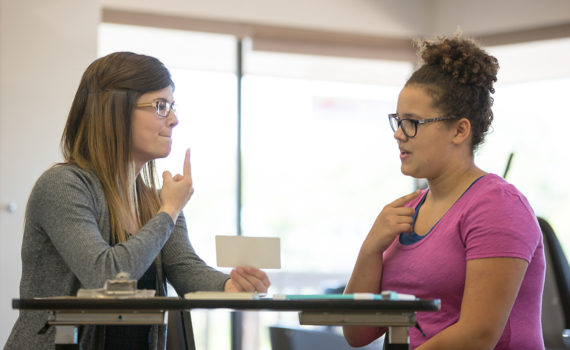 A speech pathologist helping a woman with vocal exercises.