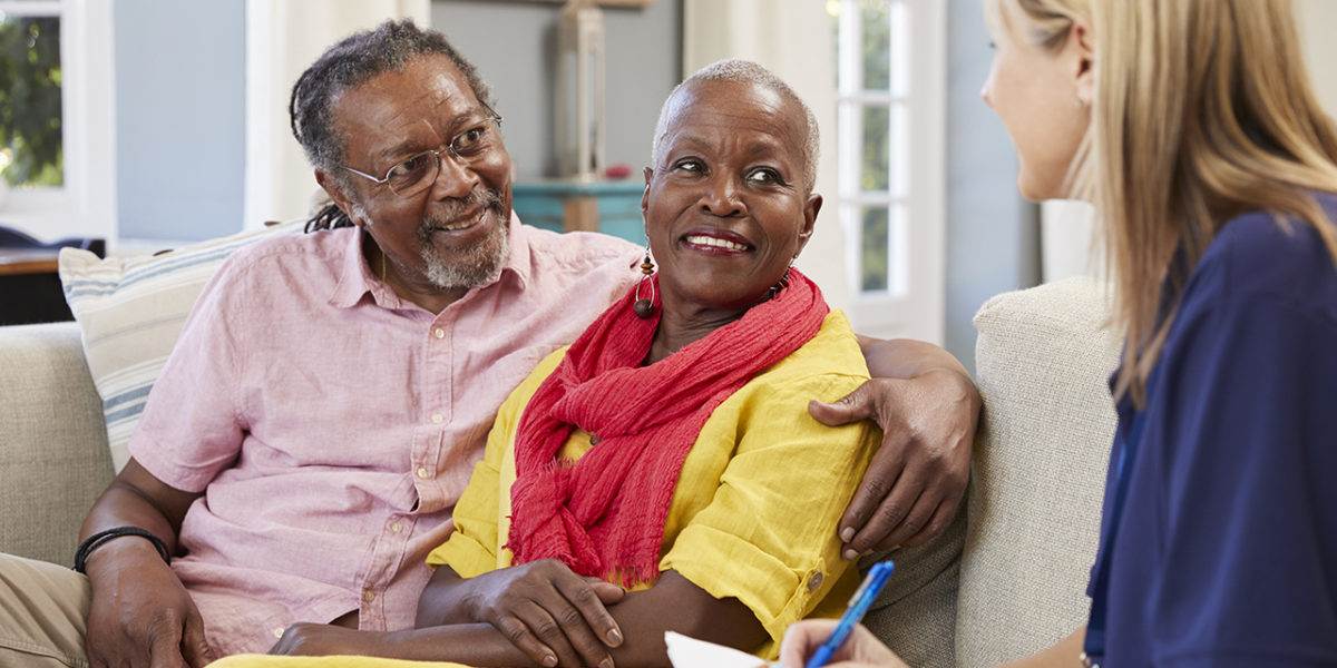 Volunteer woman speaking to a husband with his arm around his wife