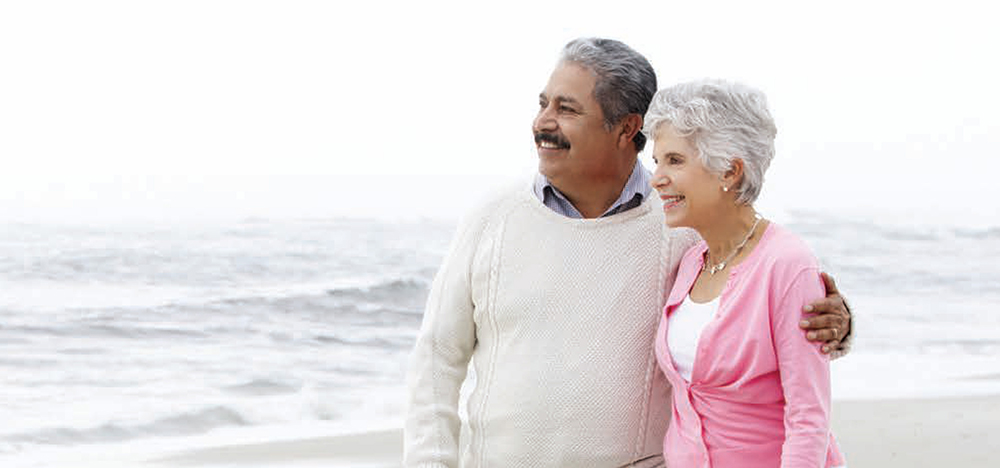 Older couple on beach arms around each other