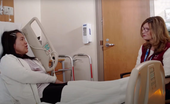 Woman volunteer visiting a woman stroke survivor in a hospital bed