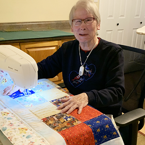 Elaine in front of sewing machine making a quilt