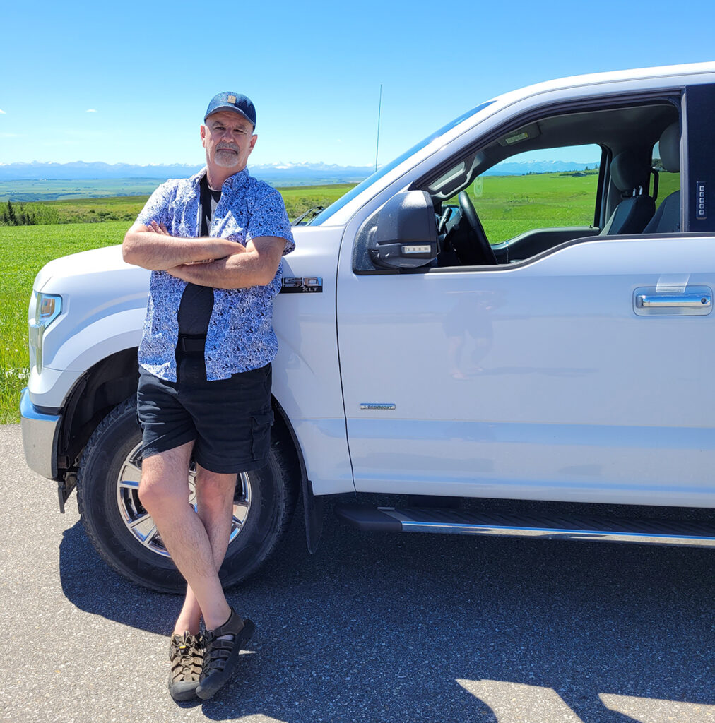 Denis leaning against his truck